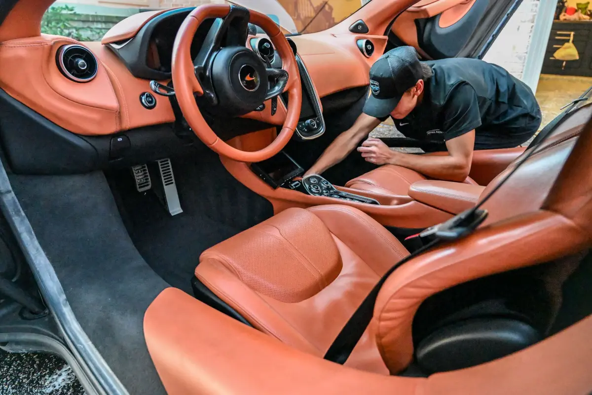 Nick cleaning the orange leather interior of the McLaren